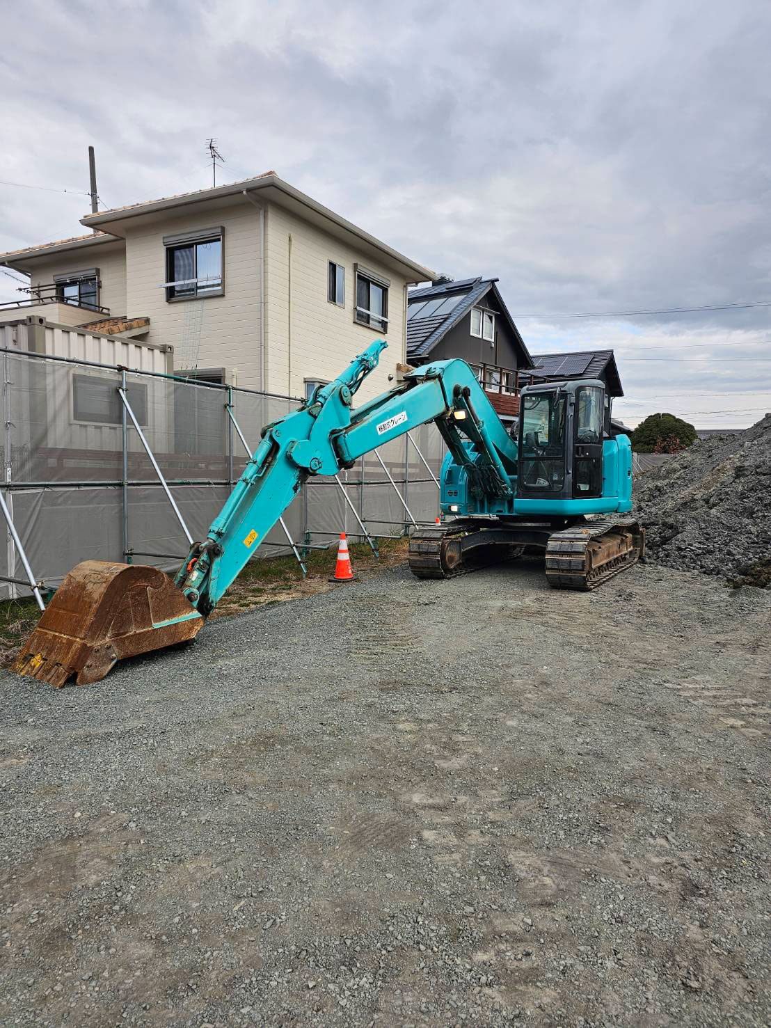住宅街の建設現場に停車しているブルーの油圧ショベル